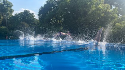 Schwimmer springen in ein Wasserbecken.