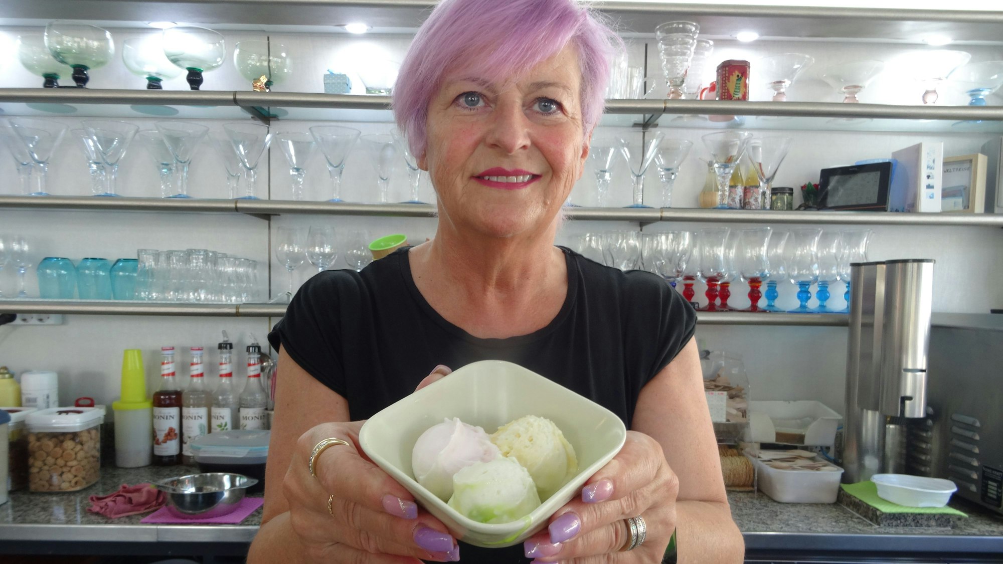 Luciana De Ronch, Chefin des Eiscafés Fontanella in Troisdorf, hält einen Eisbecher lächelnd in Richtung der Kamera.