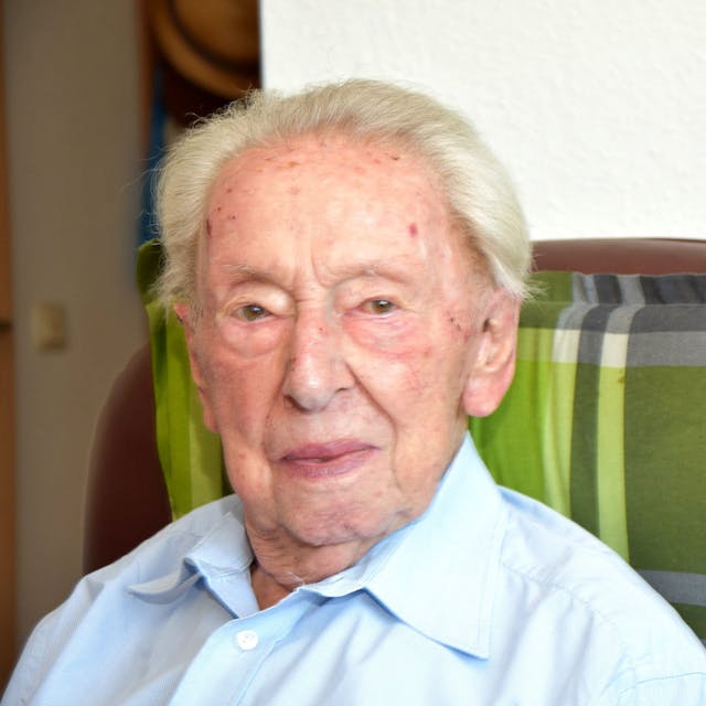 Heinz Ollig wird heute 103 Jahre alt. Er schaut an der Kamera vorbei, sitzt dabei auf einem braunen Sessel.