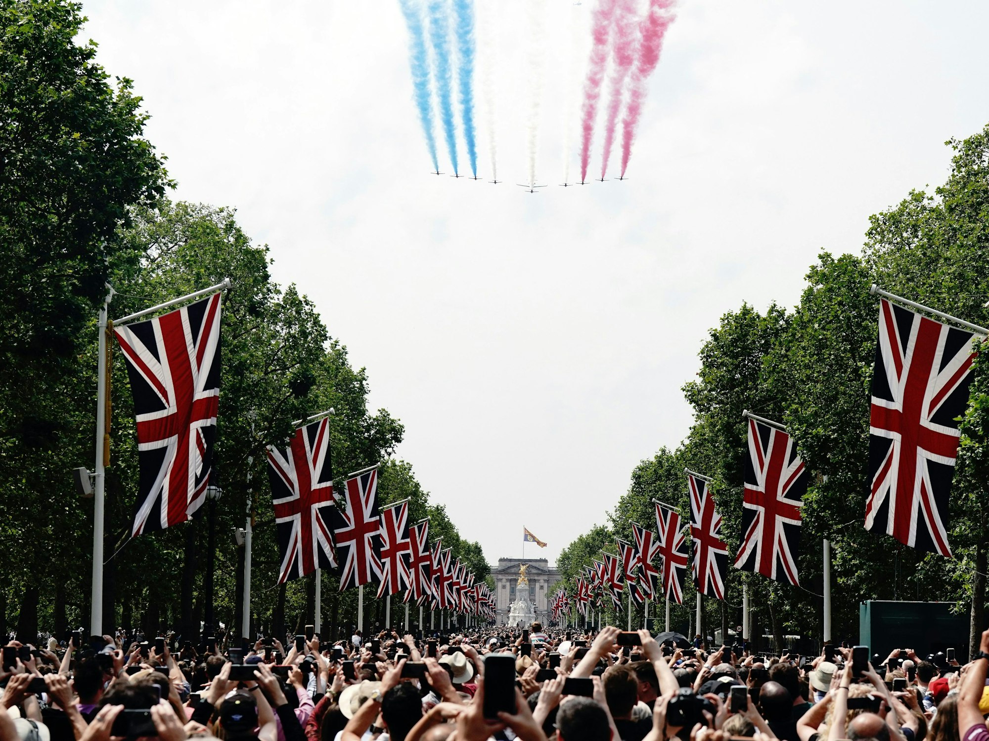 Schaulustige beobachten den Flug von Militärflugzeugen der Royal Air Force über der Prachtsstraße „The Mall“. Der Flug über den Buckingham-Palast (Hintergrund) ist Abschluss und Höhepunkt von „Trooping the Colour“.