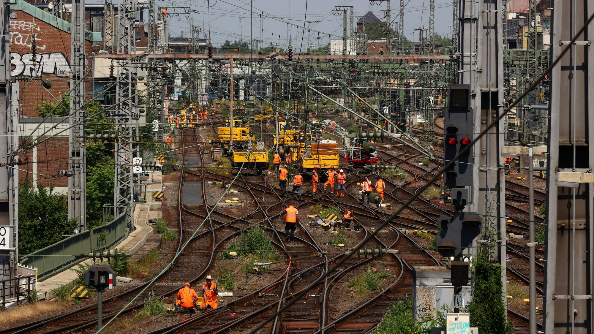 Gleise und Arbeiter in orangefarbenen Jacken sind aus der Vogelperspektive zu sehen.