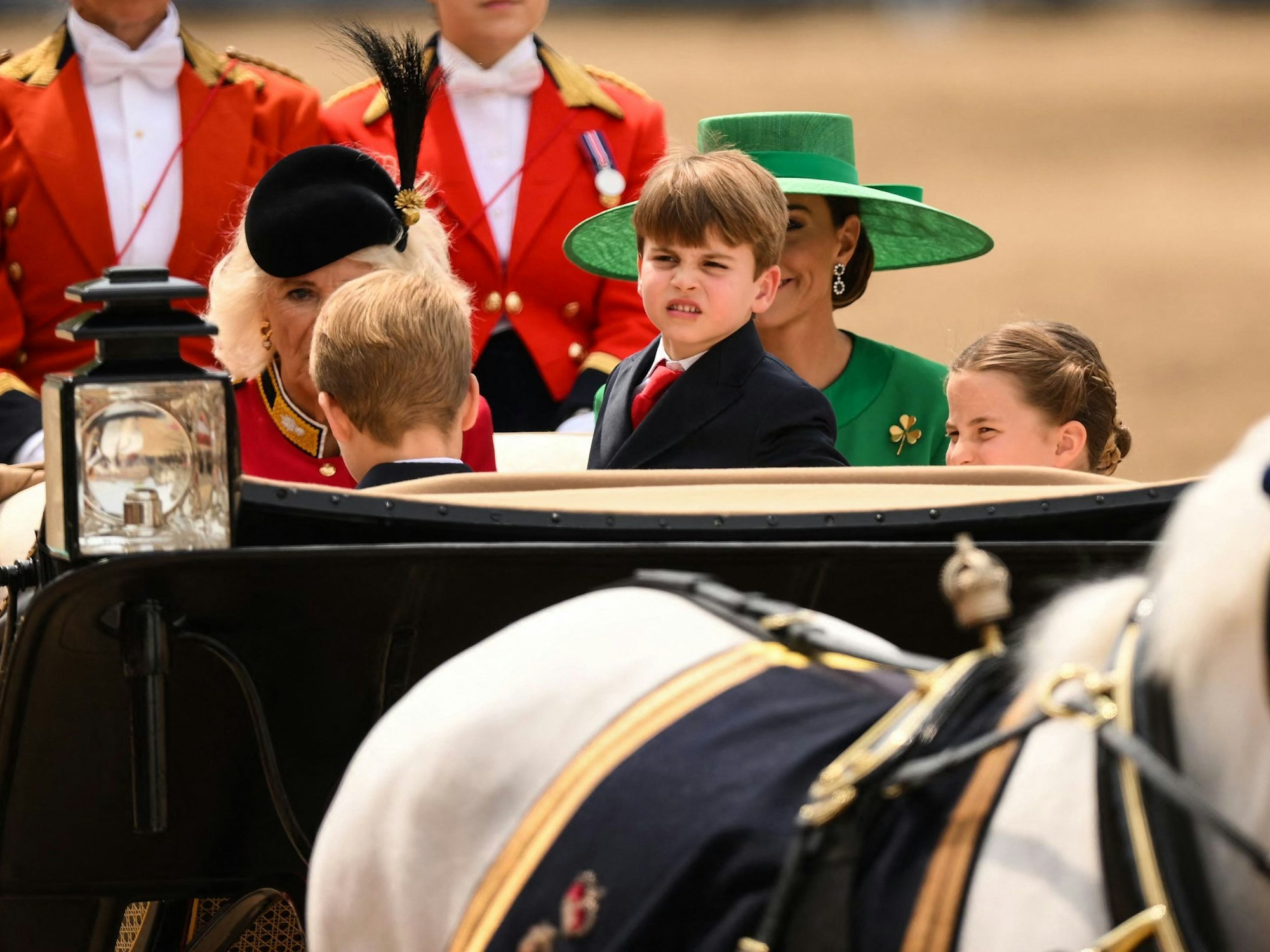Prinz George (r), Prinz Louis (m) und Prinzessin Charlotte (l) kommen in einer Pferdekutsche auf der Horse Guards Parade an.