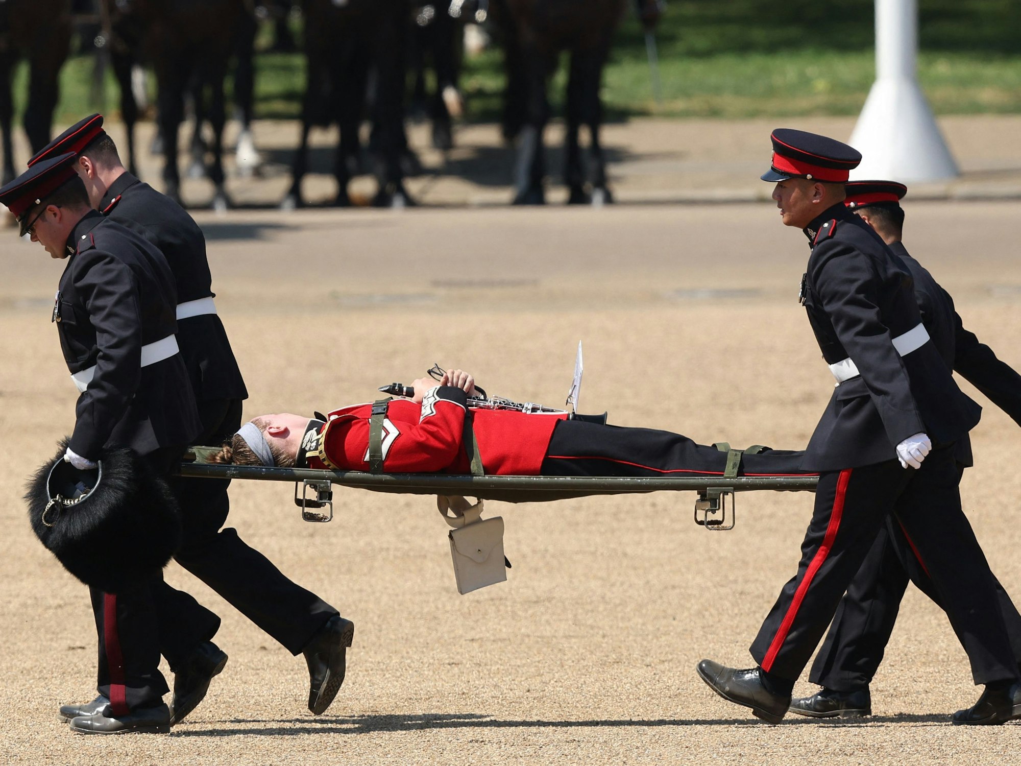 Ein Mitglied der Band wird auf einer Bahre getragen, nachdem er während der Colonel's Review auf der Horse Guards Parade in London in Ohnmacht gefallen ist.