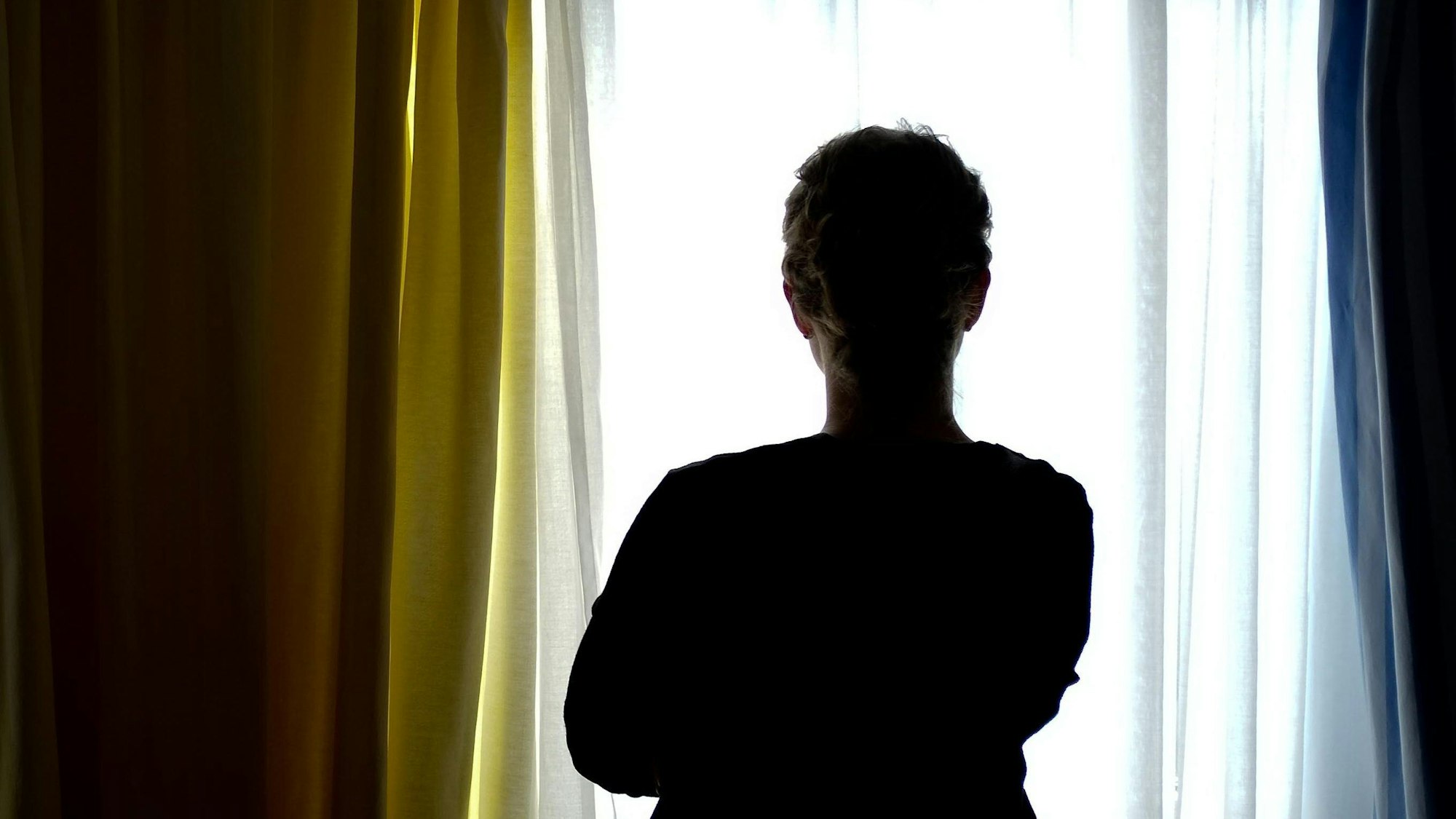 Eine junge Frau steht in einem Zimmer eines Frauenhauses (Symbolbild).