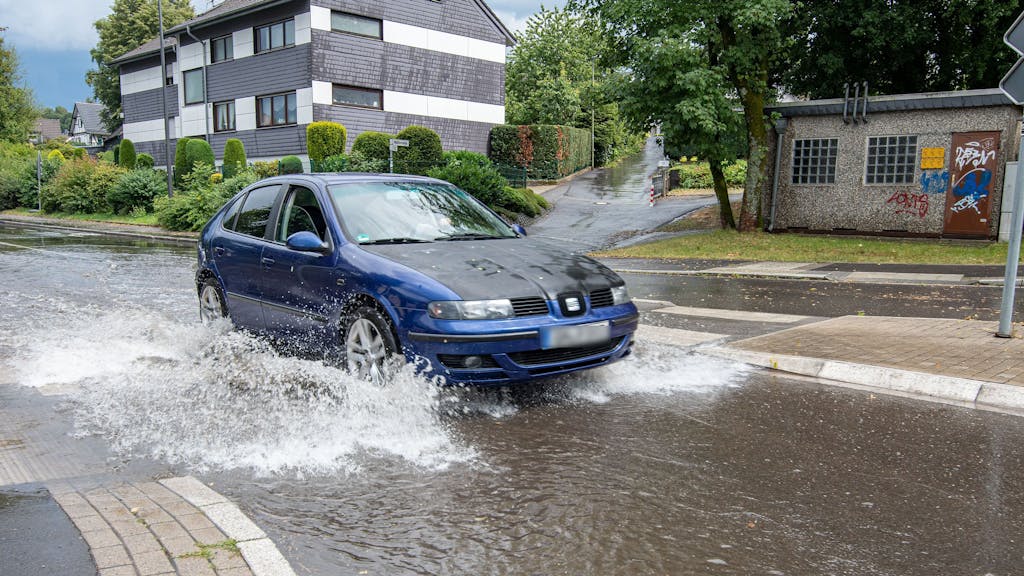 Ein Auto fährt nach Starkregen durch eine überflutete Straße. +++ dpa-Bildfunk +++