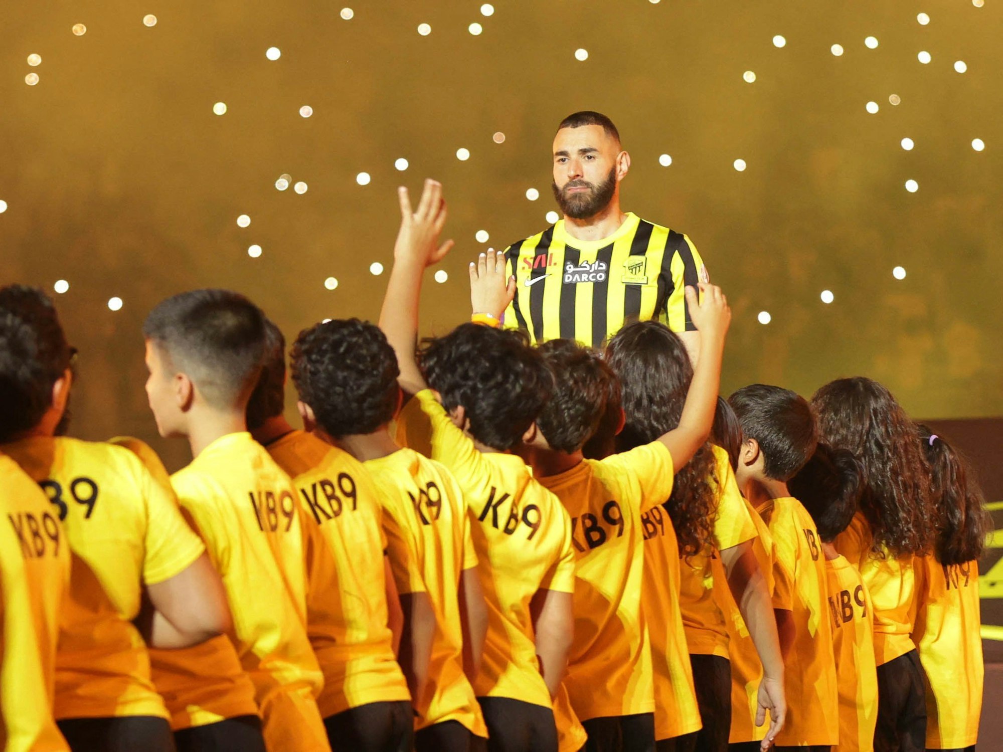 Karim Benzema ist bei der Vereinsvorstellung als neuer Al-Ittihad Spieler von Kindern umgeben.