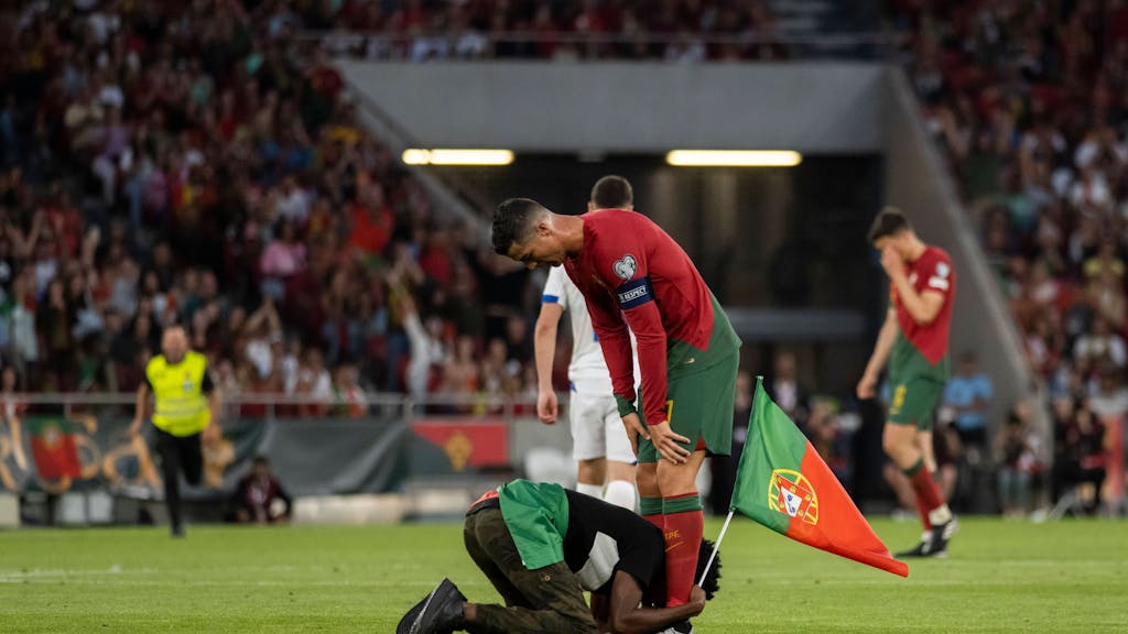 Ein Fan liegt vor Cristiano Ronaldo und klammert sich an dessen Beine.&nbsp;