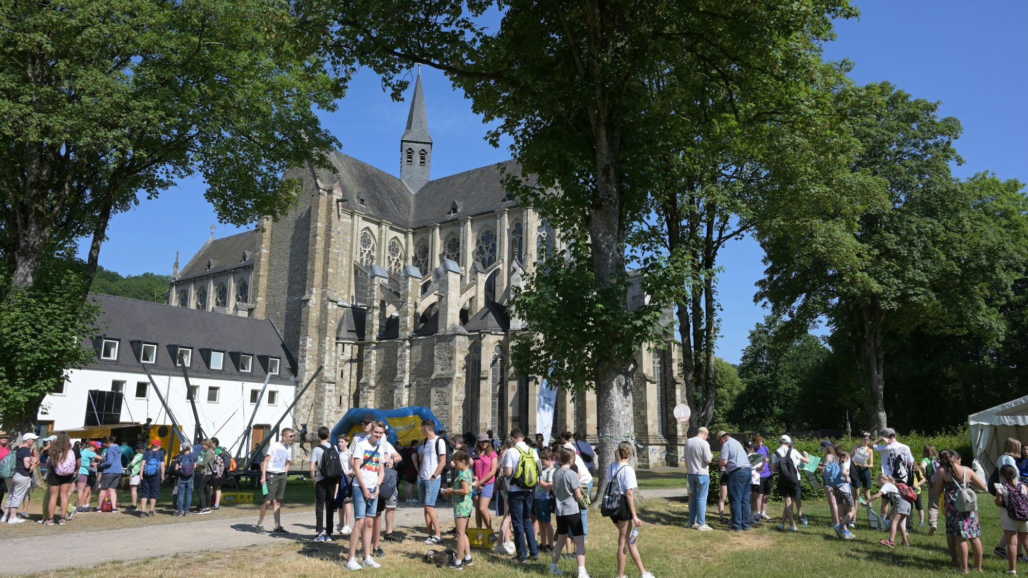 Kinder und Jugendlichge stehen mit Rucksäcken auf der Wiese am Fuße des Altenberger Doms.