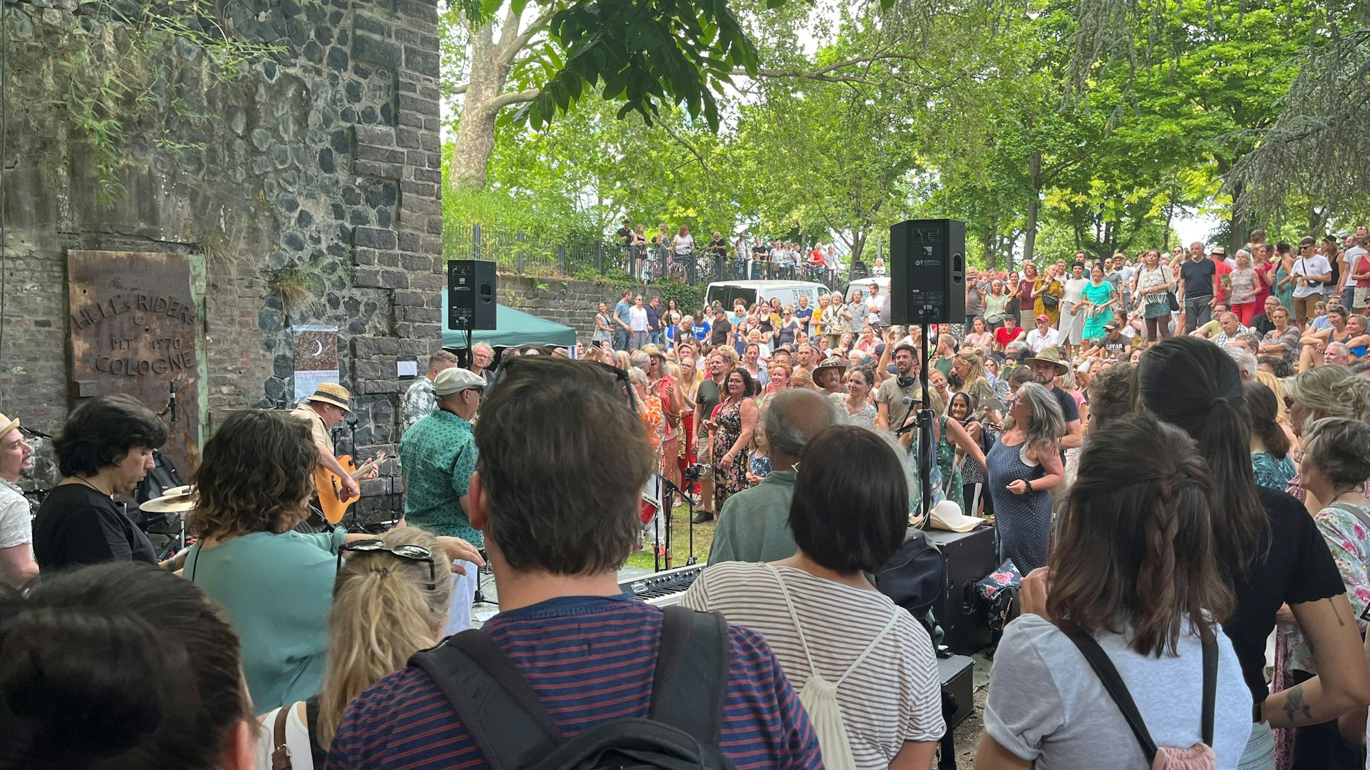 Viele Menschen stehen um eine Band in einem Park.