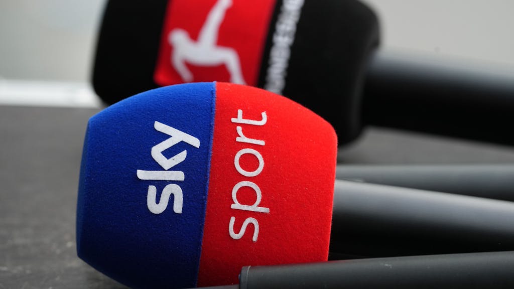 Zwei Mikrofone mit den Logos von Sky Sport und Fußball-Bundesliga liegen auf einem Pult.