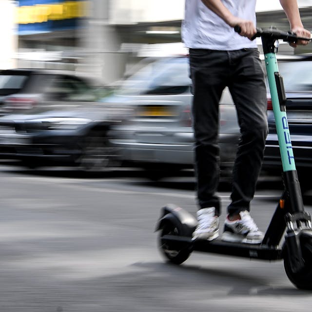Ein Mann fährt mit einem E-Scooter auf der Straße.