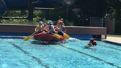 Ein mit Personen besetztes Schlauchboot im Swimming Pool.