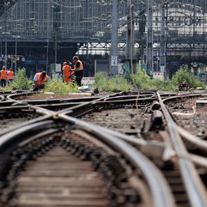 Der Kölner Hauptbahnhof wird am Sonntag komplett gesperrt. Auf dem Bild ist die Einfahrt aus Schienenperspektive zu sehen. Bauarbeiter in orangen Westen werkeln an Gleisen.