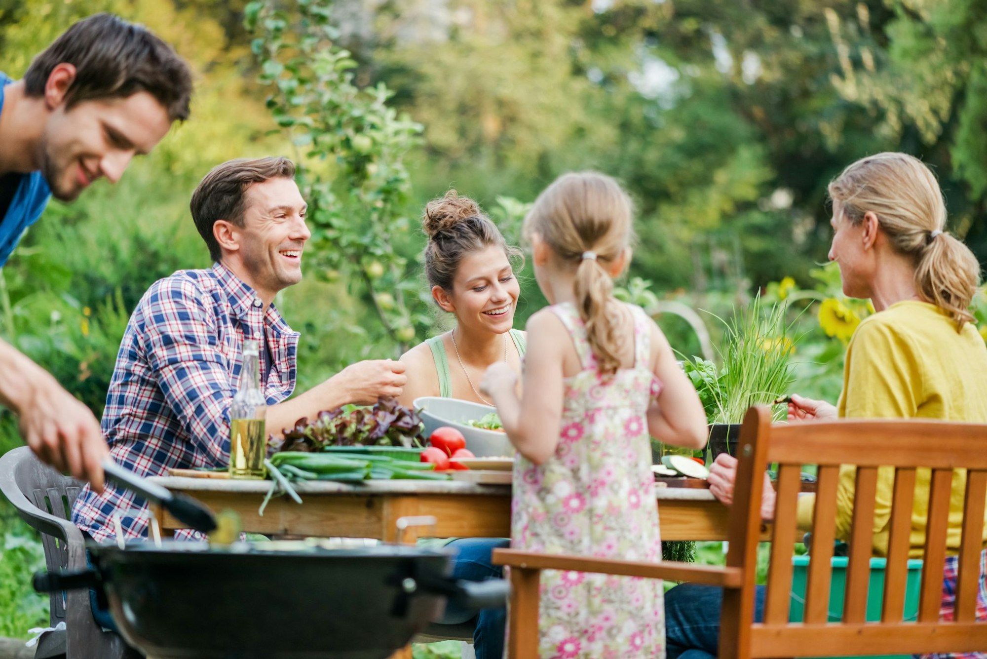Familie sitzt im Garten beim Essen