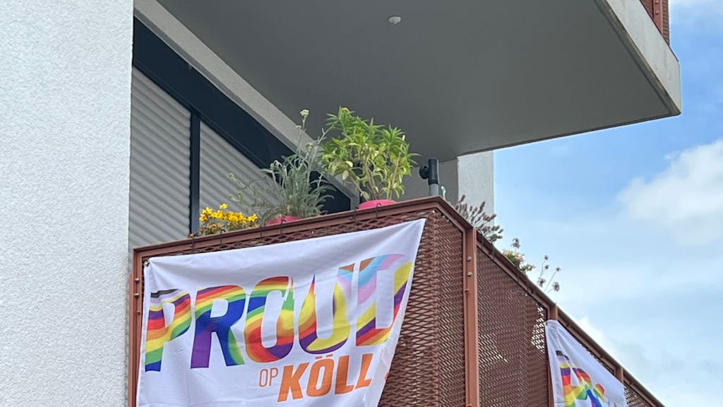 Fahnen mit der Aufschrift „Proud op Kölle“ hängen an einem Balkon in Köln-Nippes.
