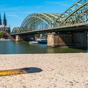 Kölschglas am Rhein. Im Hintergrund die Hohenzollernbrücke und der Dom.