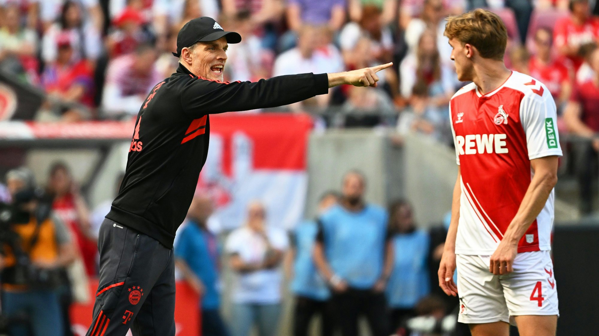 Bayerns Trainer Thomas Tuchel reagiert an der Seitenlinie, Kölns Timo Hübers schaut genau hin.