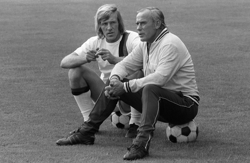 Hennes Weisweiler (r.), Trainer-Legende von Borussia Mönchengladbach, im Gespräch mit seinem Spielmacher Günter Netzer (l.). Dieses Foto zeigt die beiden am 25. Juli 1971. Die beiden sitzen jeweils auf einem Fußball.