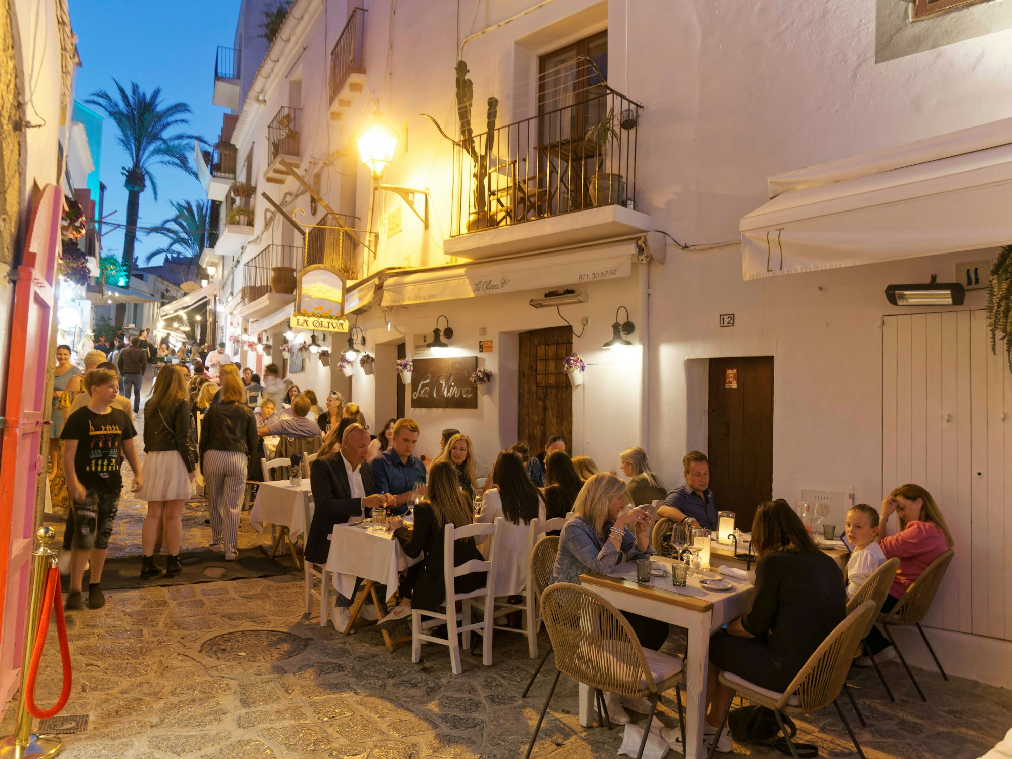 Menschen sitzen draußen an Restauranttischen auf Ibiza.