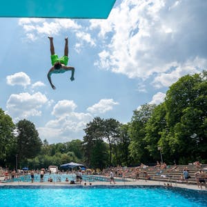 Ein Mann springt kopfüber vom Sprungbrett ins Becken des Kölner Stadionbad.