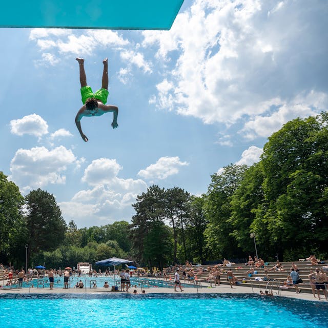 Ein Mann springt kopfüber vom Sprungbrett ins Becken des Kölner Stadionbad.