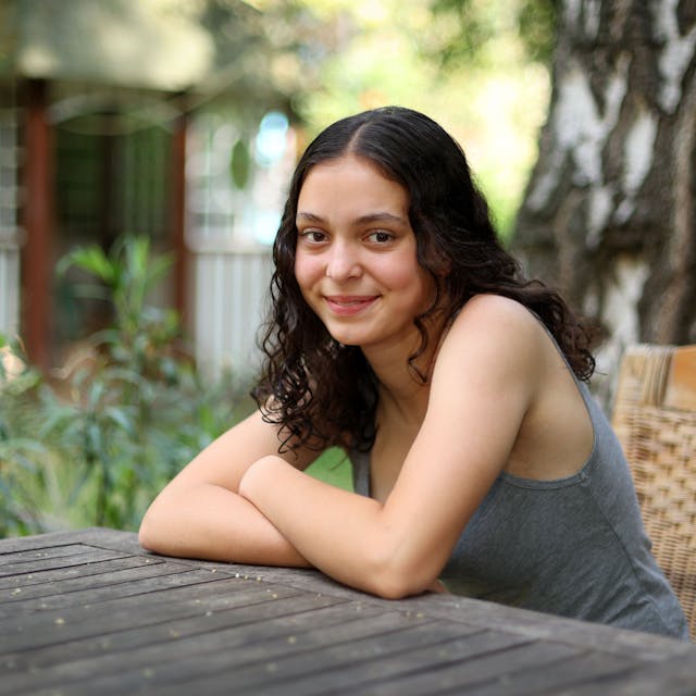 Marlene Skupch (16) aus Neu-Ehrenfeld sitzt in einem Sommergarten am Holztisch.

