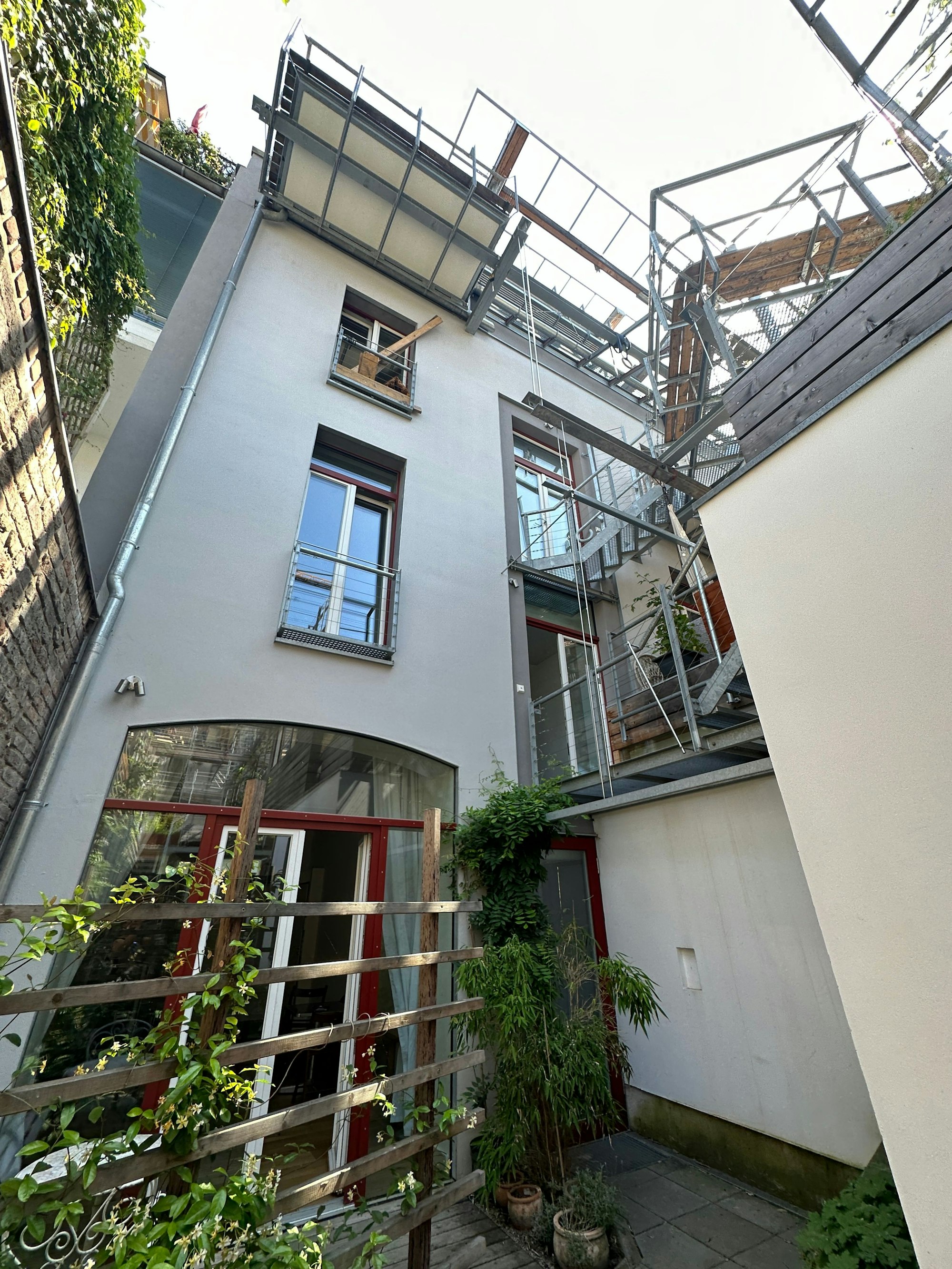 Im kleinen Innenhof ist ein Rankgitter zu sehen, eine Treppe führt zur Dachterrasse.