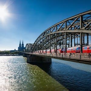Blick auf die von der Sonne angestrahlte Hohenzollernbrücke über den Rhein, im Hintergrund der Kölner Dom