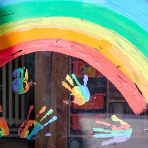 Kinderhände und ein Regenbogen sind an einer Kita zu sehen.&nbsp;