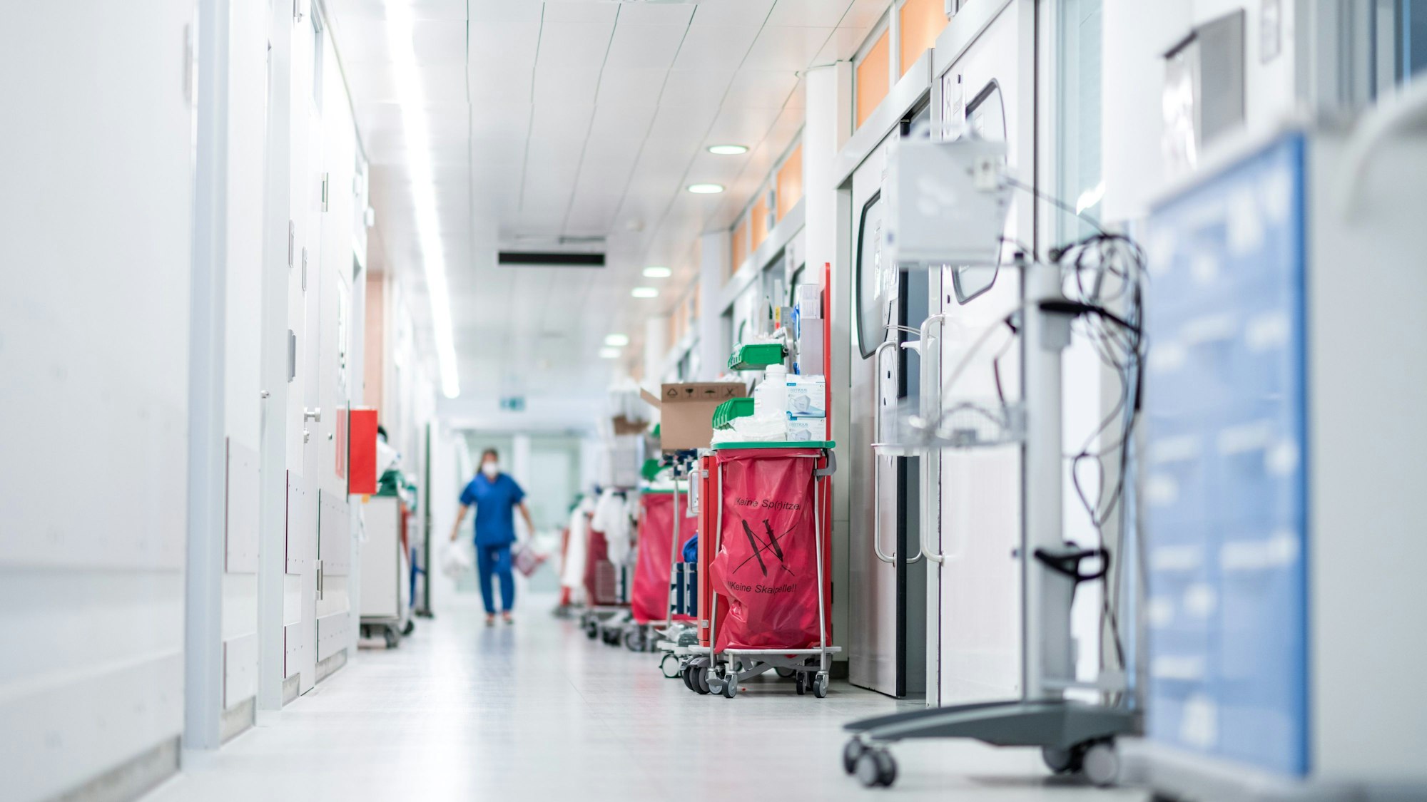 Eine Mitarbeiterin der Pflege läuft über einen Gang auf der Corona-Intensivstation des Universitätsklinikums Essen. Die Deutsche Krankenhausgesellschaft hat vor akuten Finanznöten vieler Kliniken gewarnt.
