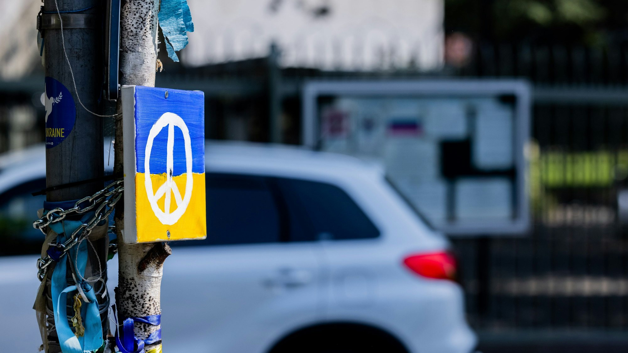 Ein Peace-Zeichen auf einer ukrainischen Flagge an einem Straßenschild in Bonn