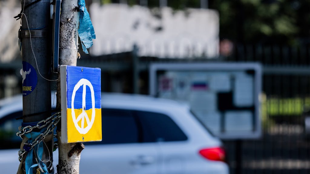 Ein Peace-Zeichen auf einer ukrainischen Flagge an einem Straßenschild in Bonn