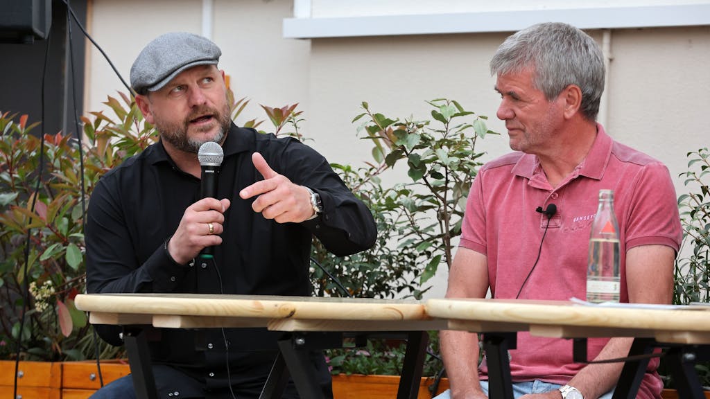 Steffen Baumgart sitzt mit Mikrofon neben Friedhelm Funkel.