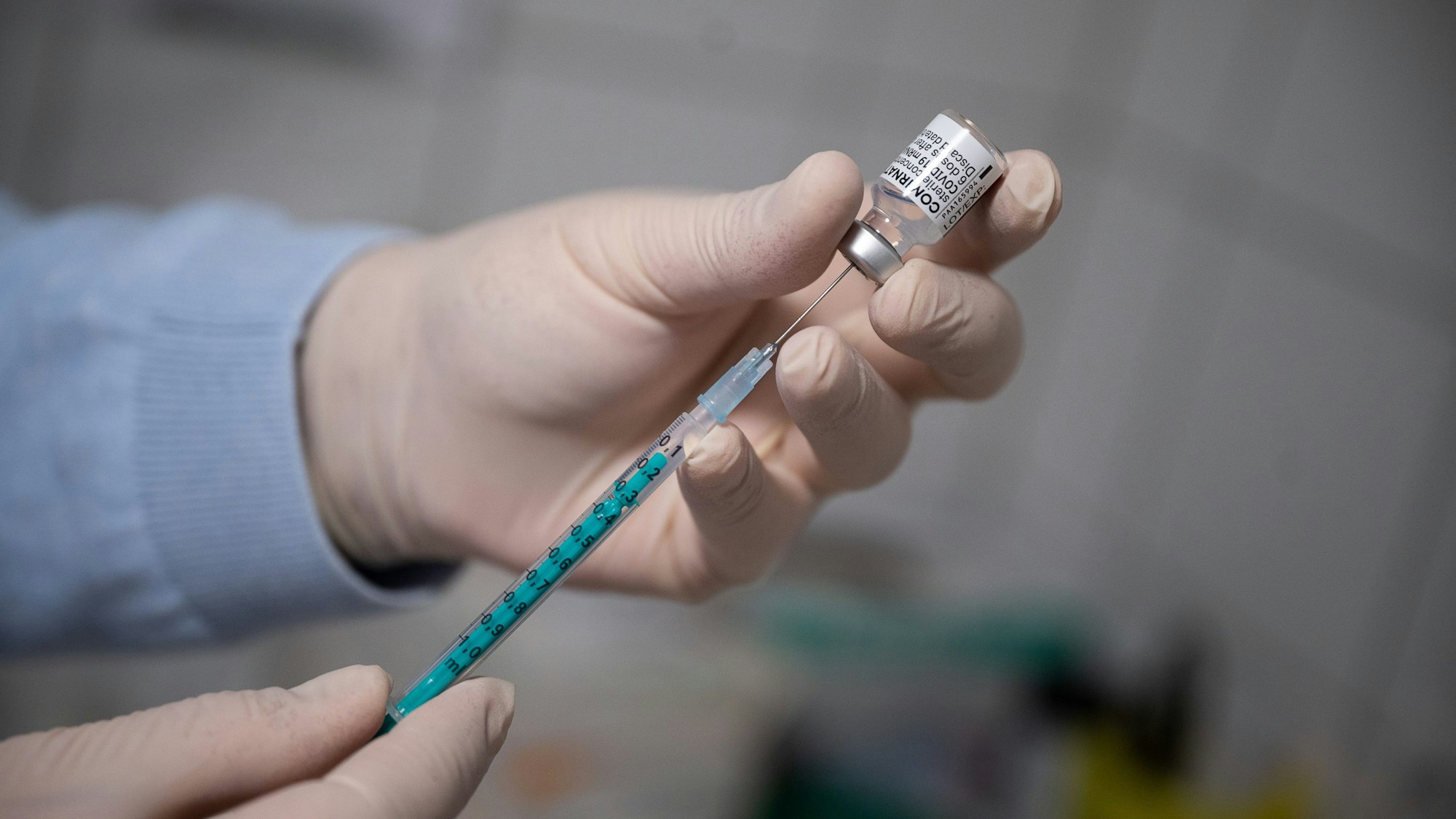 Ein Arzt zieht in einer Hausarztpraxis eine Spritze mit dem Corona-Impfstoff auf.