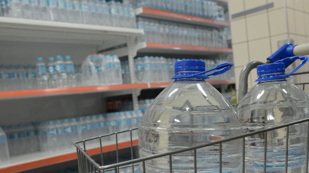 Wasserflaschen stehen in einem Einkaufswagen und auf einem Regal in einem Supermarkt in Rio de Janeiro.