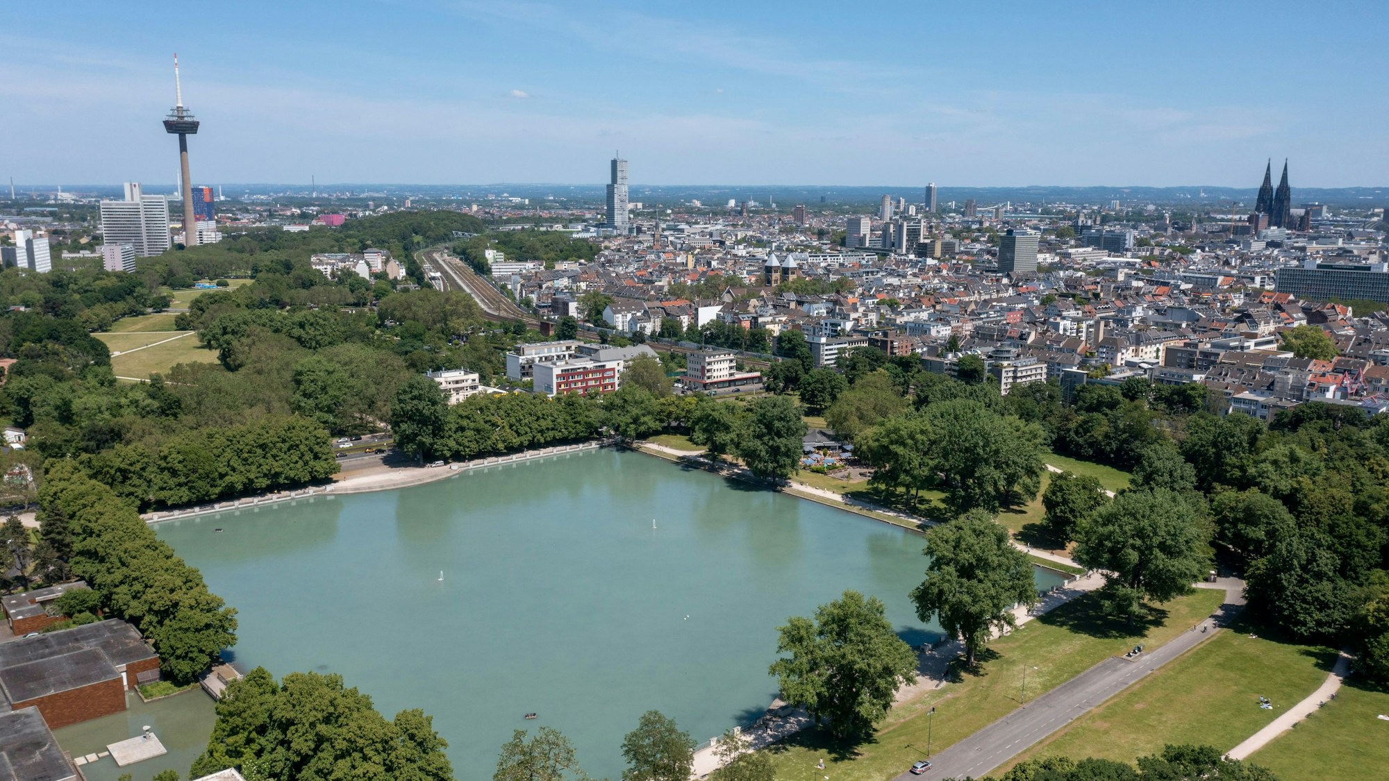 Der Aachener Weiher und das Stadtpanorama. Im Hintergrund sind der Colonius, der Köln-Tower im Mediapark und der Kölner Dom zu erkennen.