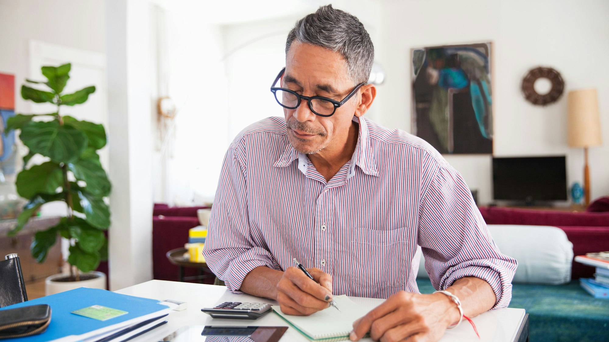 Ein Mann mit Brille arbeitet zu Hause an seinen persönlichen Finanzen.
