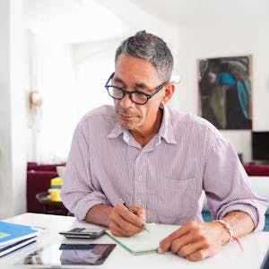 Ein Mann mit Brille arbeitet zu Hause an seinen persönlichen Finanzen.