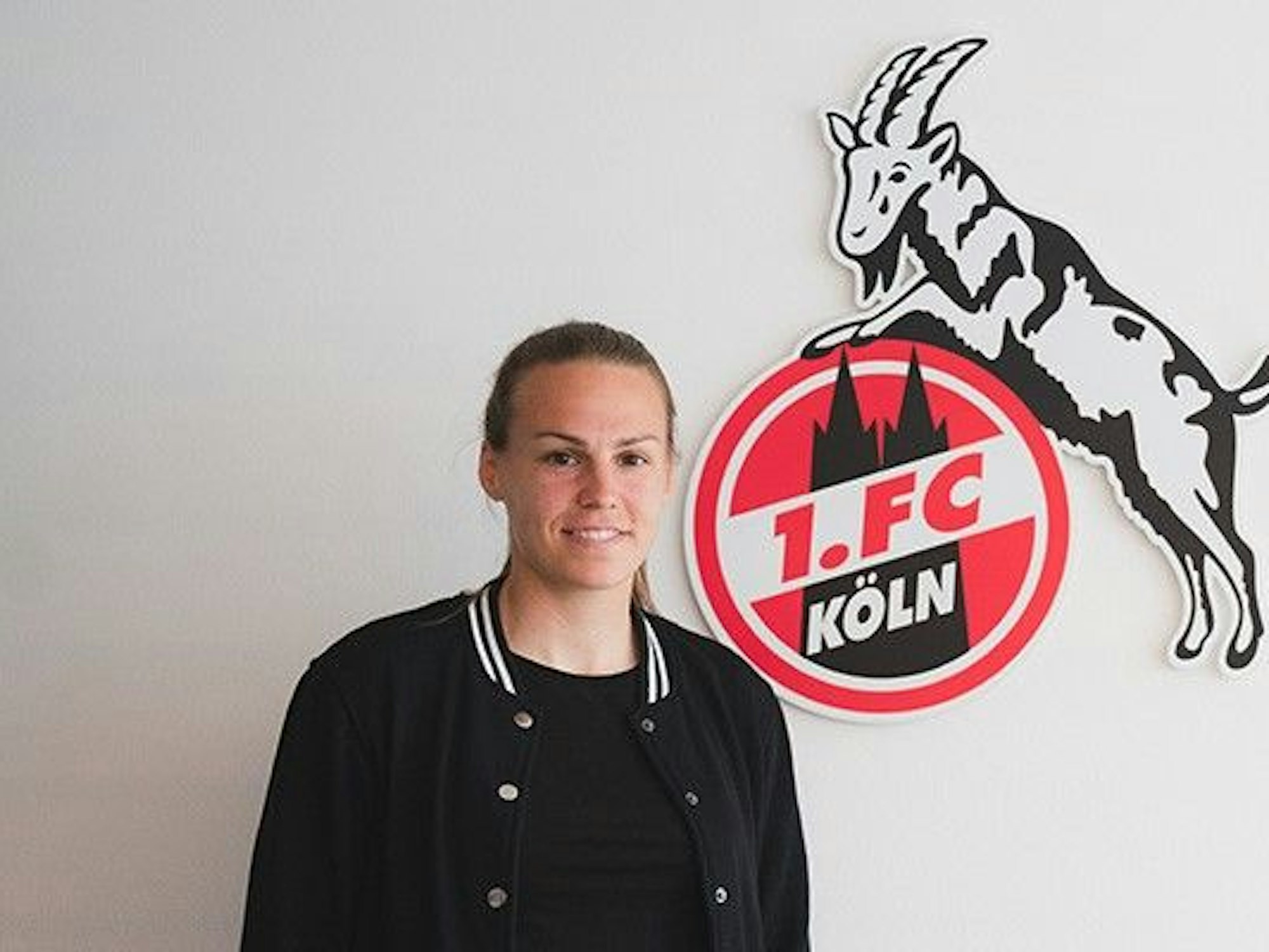 Dora Zeller vor dem Logo des 1. FC Köln.