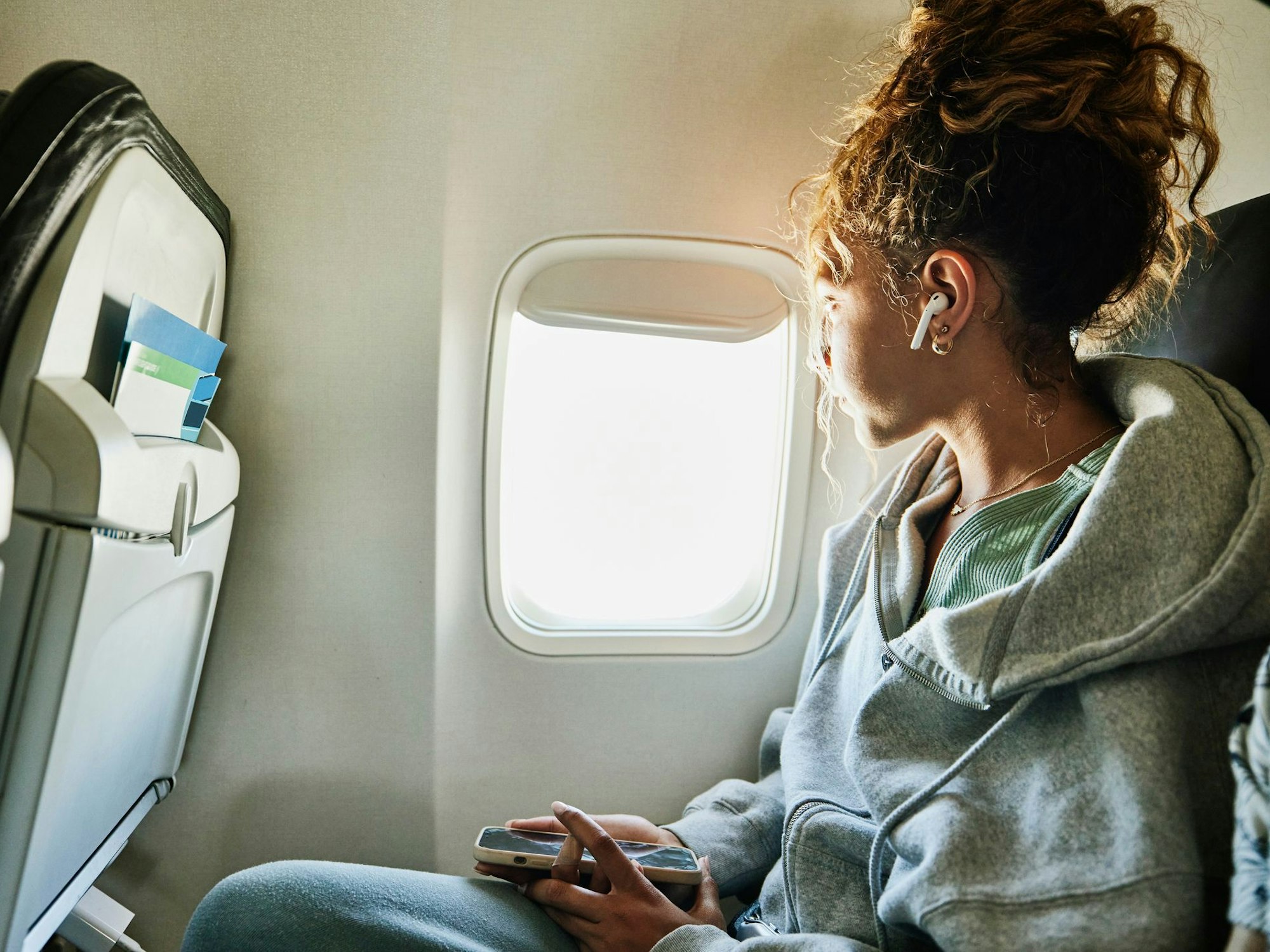 Eine Frau guckt im Flugzeug aus dem Fenster.