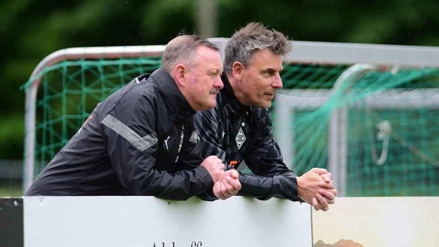 Roland Virkus (l.) und Steffen Korell stehen im Trainingslager von Borussia Mönchengladbach am 4. Juli 2022 am Spielfeldrand.