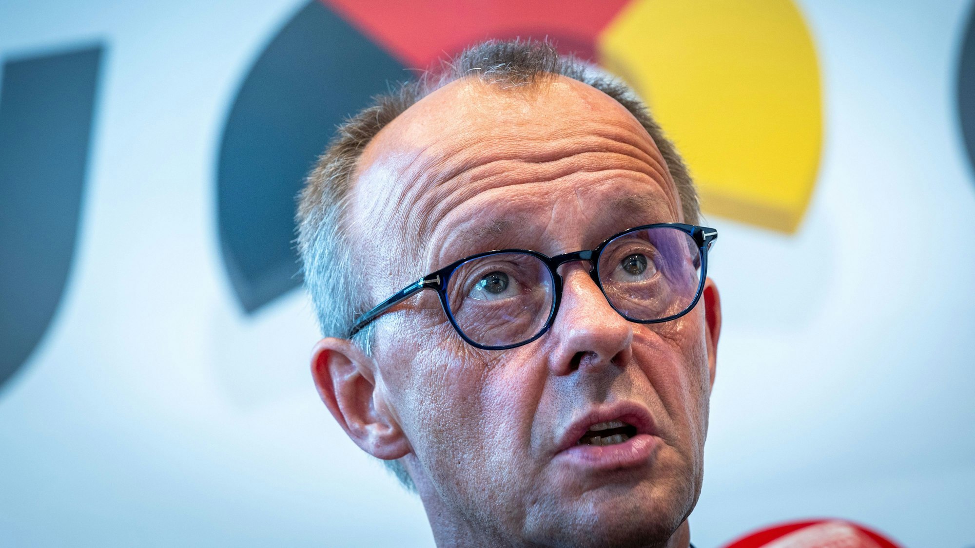 Friedrich Merz, Vorsitzender der CDU, sitzt vor einer Wand mit dem Logo der Partei bei einer Pressekonferenz.
