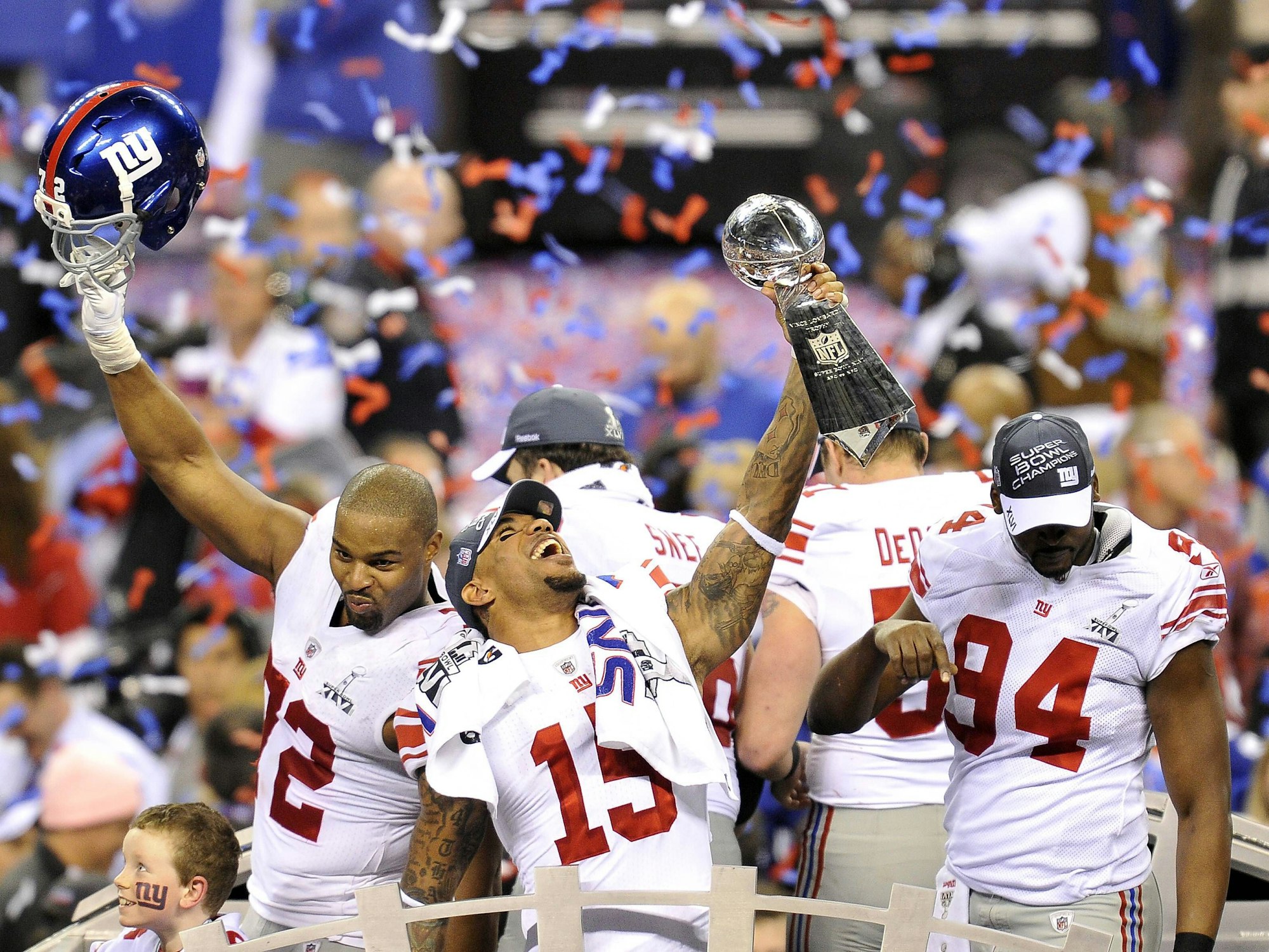 Ein Spieler der New York Giants hält die Vince Lombardi Trophy in die Höhe, während seine Mitspieler feiern.