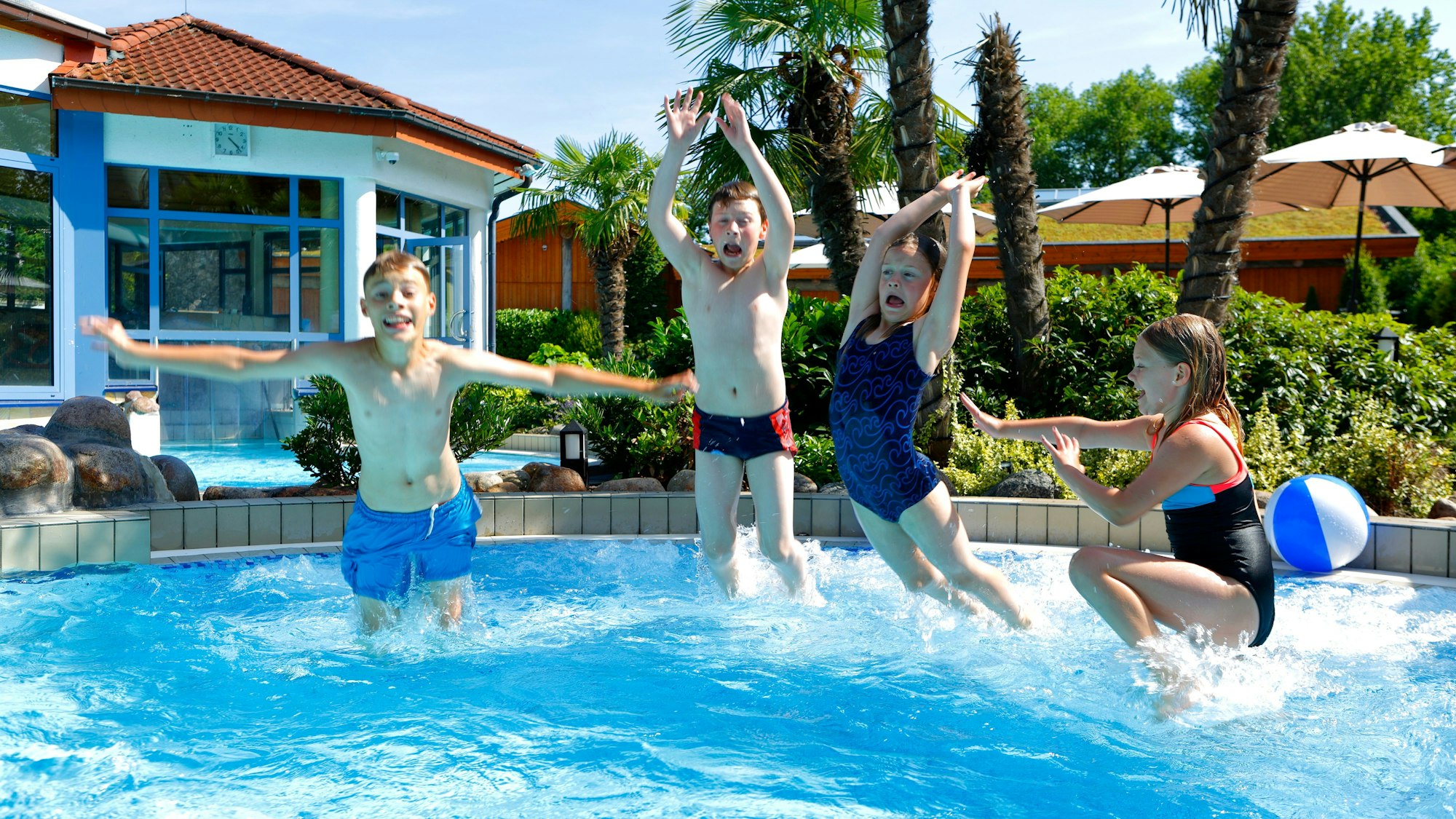 vier Kinder springen in ein Schwimmbecken