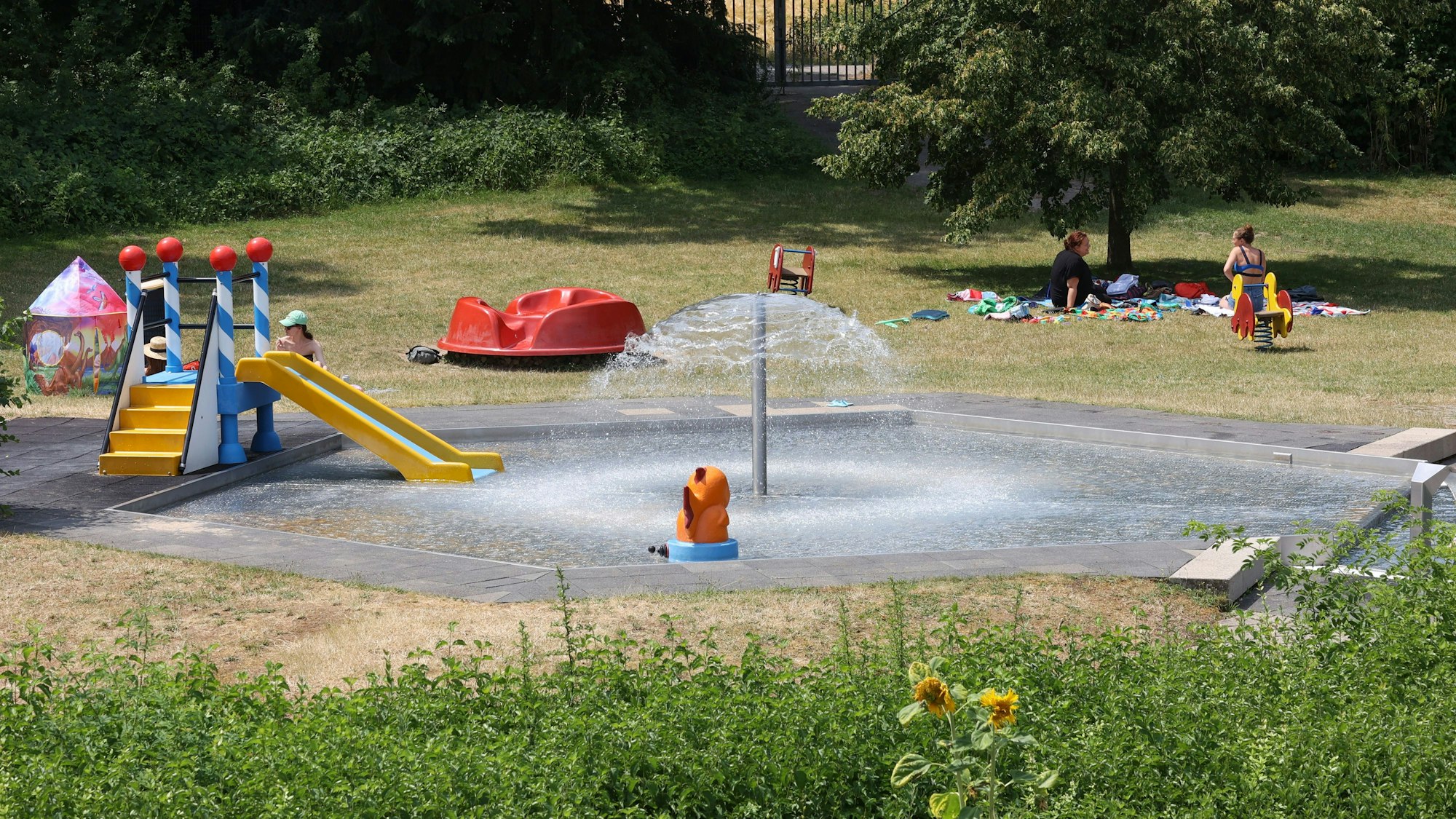 Eine Rutsche, Karussell und ein Wasserpilz bilden neben dem Plantschbecken die Kinderlandschaft im Zündorfbad.