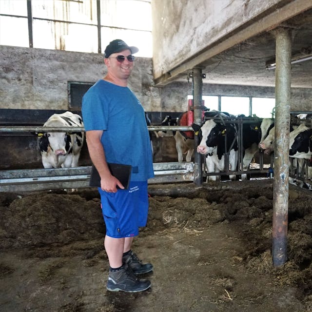 Landwirt Sebastian Bützler steht im Stall bei seinen Kühen.