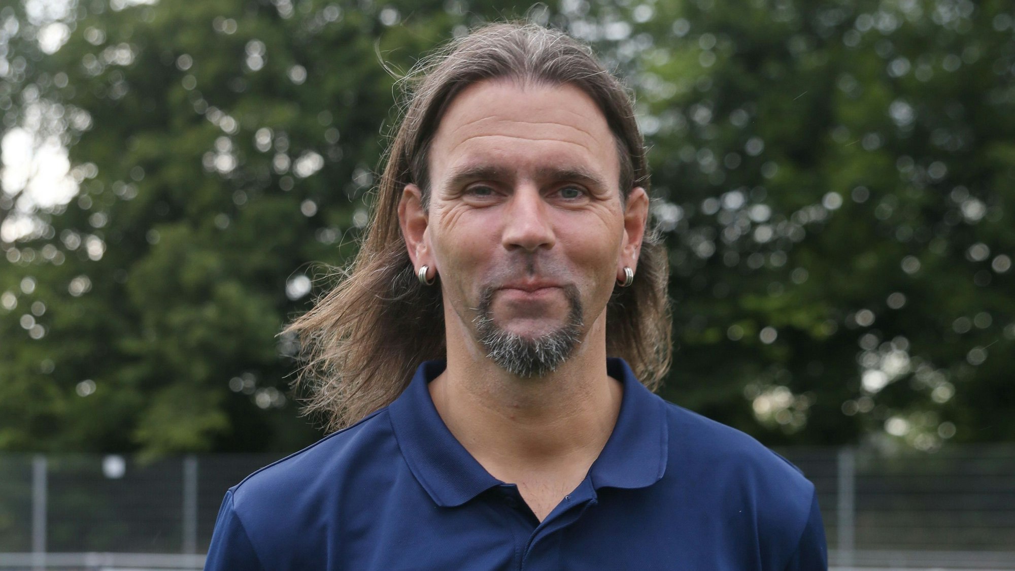 Porträt eines Fußballtrainers mit langen Haaren.