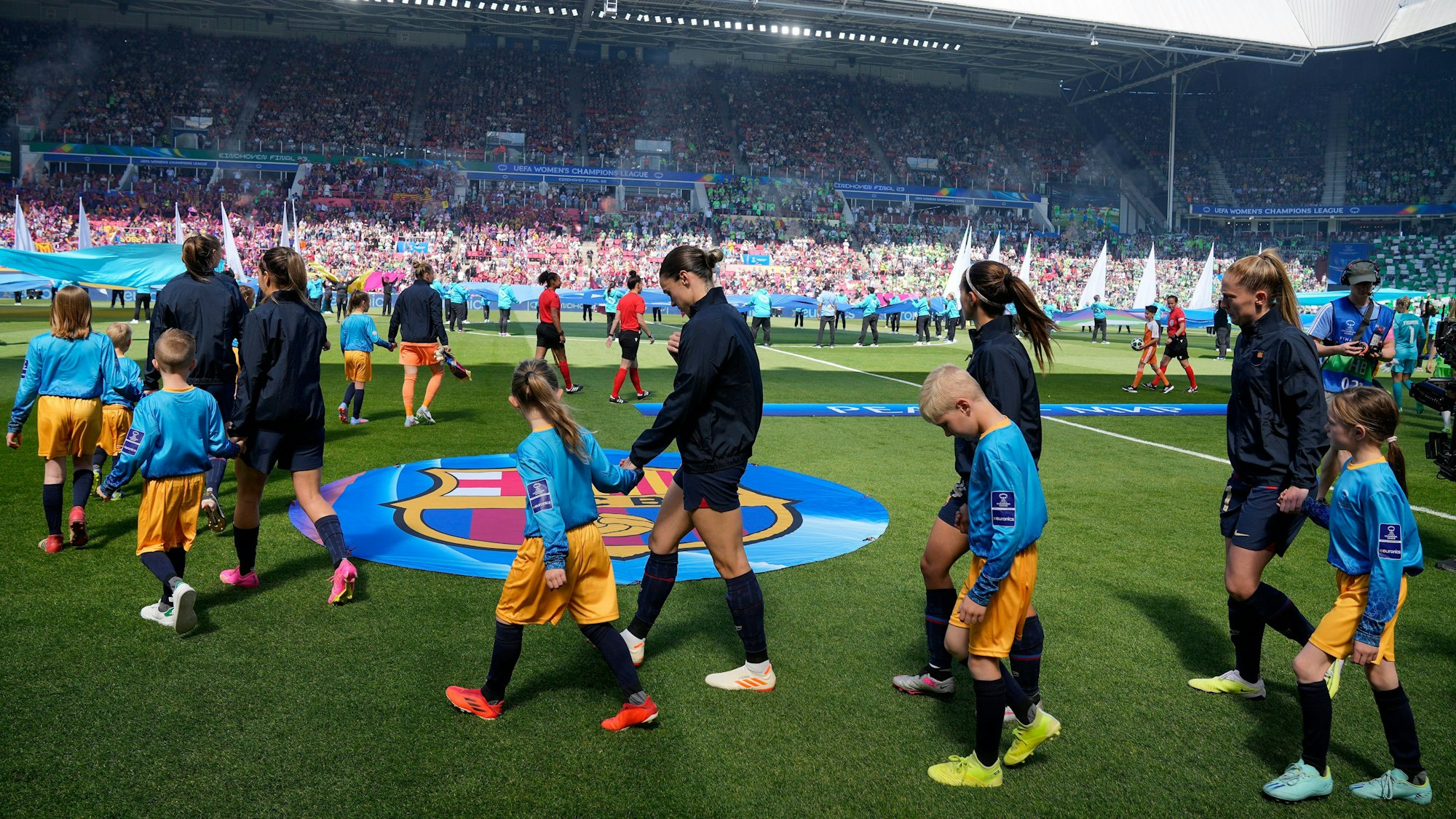 Die Spielerinnen des FC Barcelona laufen mit Kindern an der Hand auf den Rasen.