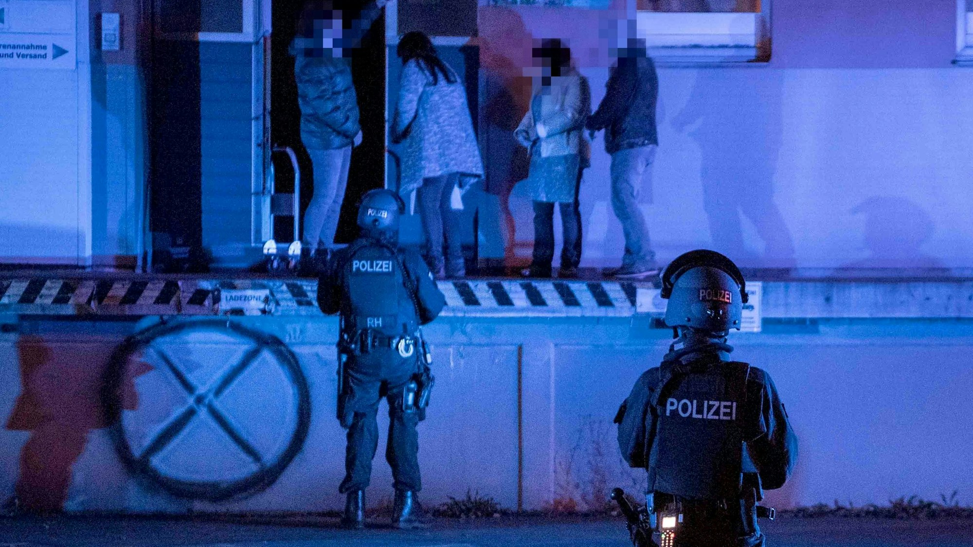 Zivilpolizisten verhaften bei der Razzia in einer ehemaligen Molkerei in Euskirchen-Kuchenheim zwei Frauen, die dort in der Cannabis-Plantage gearbeitet haben. Zwei bewaffnete SEK-Beamte sichern die Rampe der Lagerhalle.