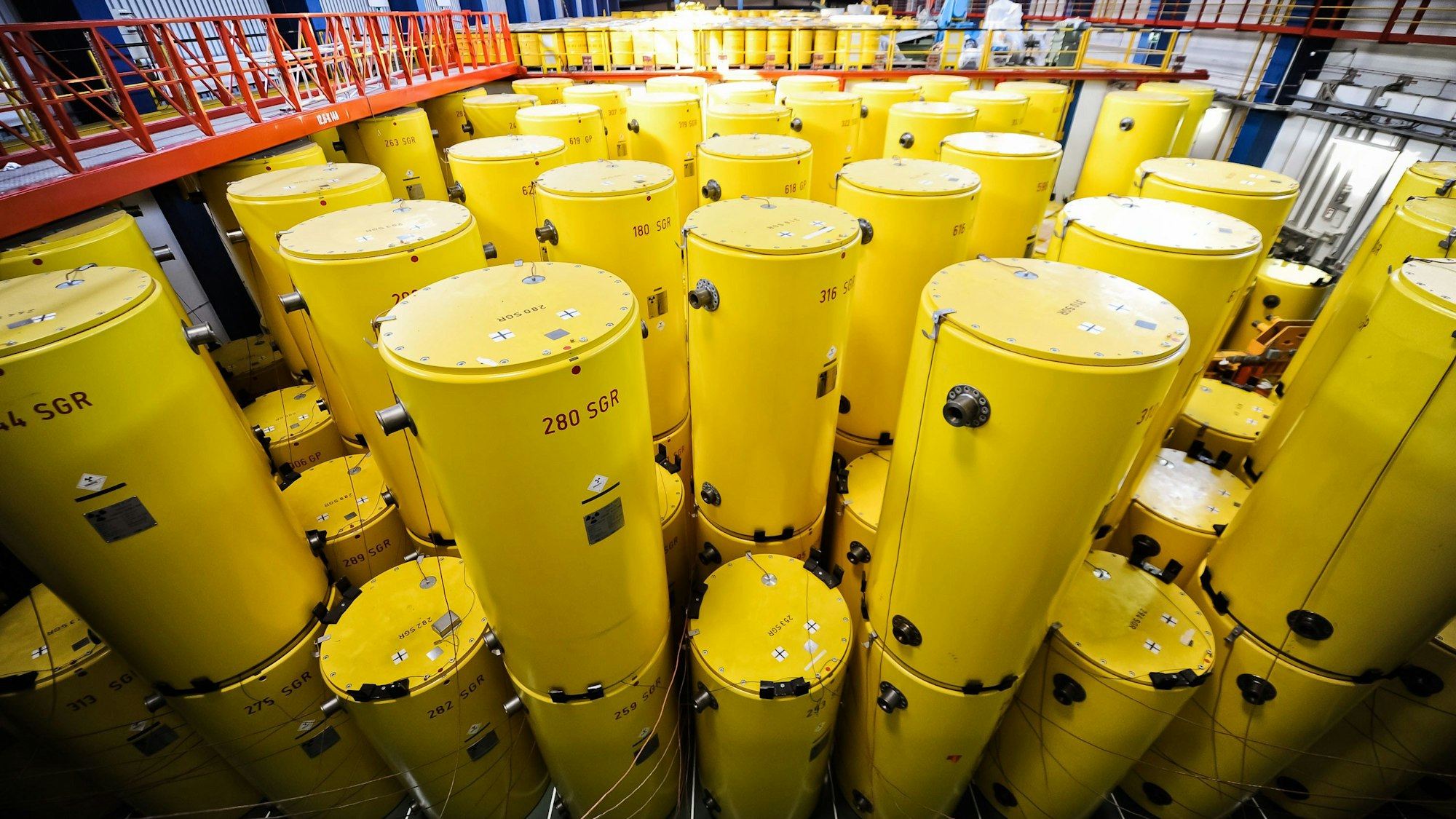 Etliche gelbe, zylindrische Castor-Behälter stehen in einer Lagerhalle.